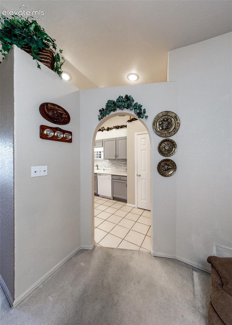 Architectural arched pass-through featuring recessed lighting, neutral wall finishes, and ceramic tile flooring