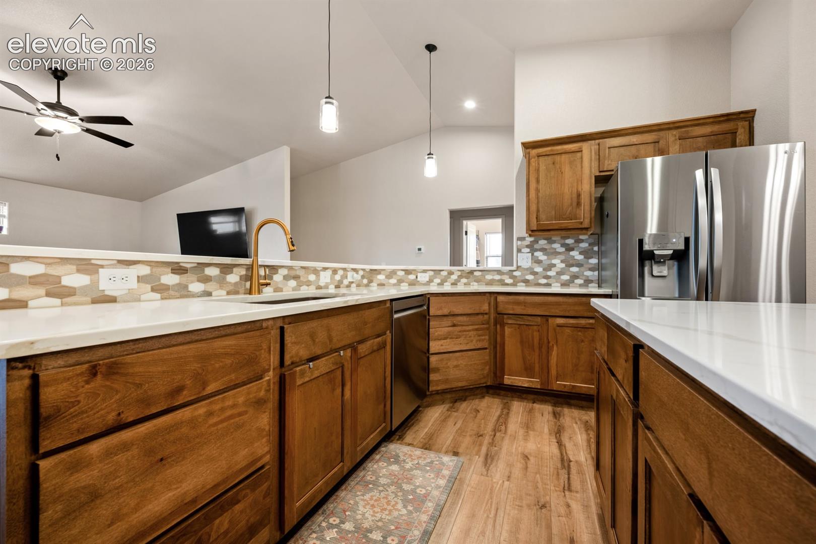 Kitchen featuring wood cabinetry, white countertops, a hexagonal tile backsplash, stainless steel appliances, and pendant lighting