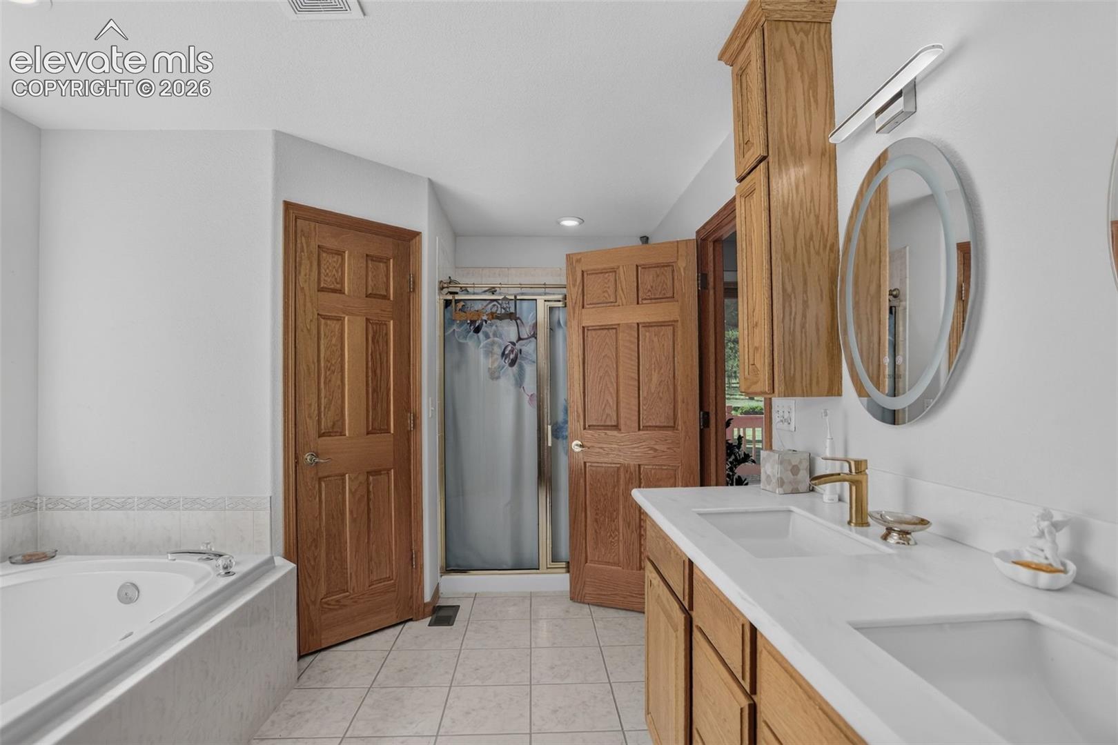 Primary bathroom with jetted tub, double vanity, and free standing shower.