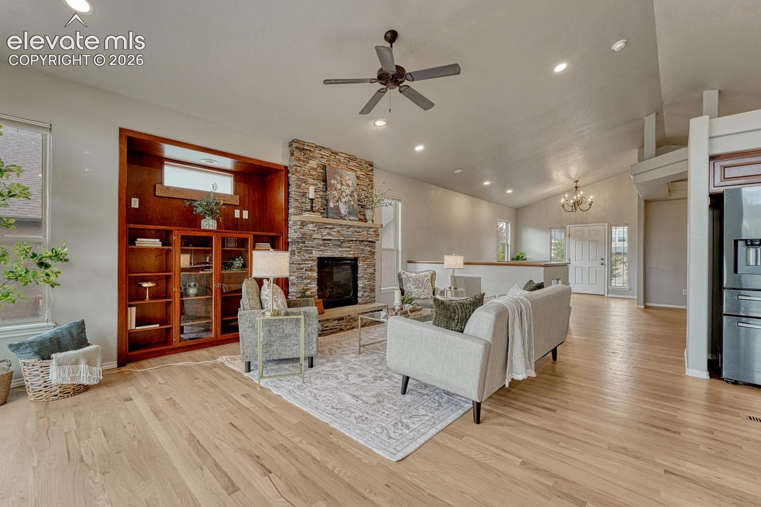 The spacious Great Room features wood flooring, a ceiling fan, custom built-ins, and a a gas fireplace.