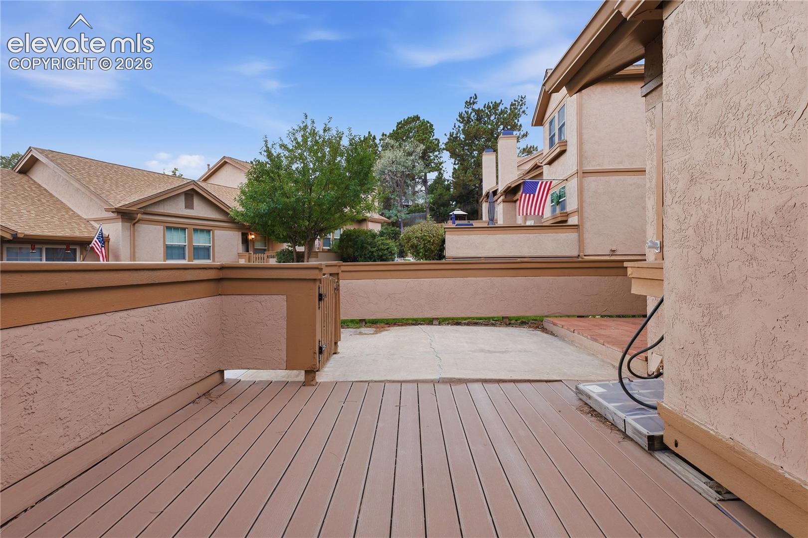Spacious outdoor deck featuring composite decking and a stucco wall with a wood-finish cap