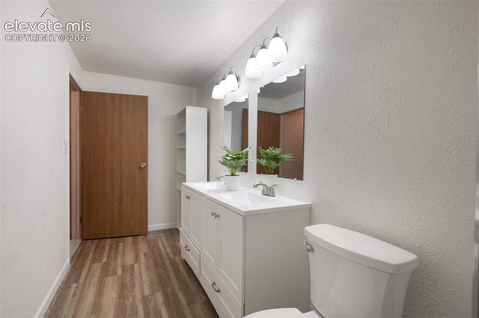 Bathroom featuring wood finished floors, toilet, vanity, and baseboards