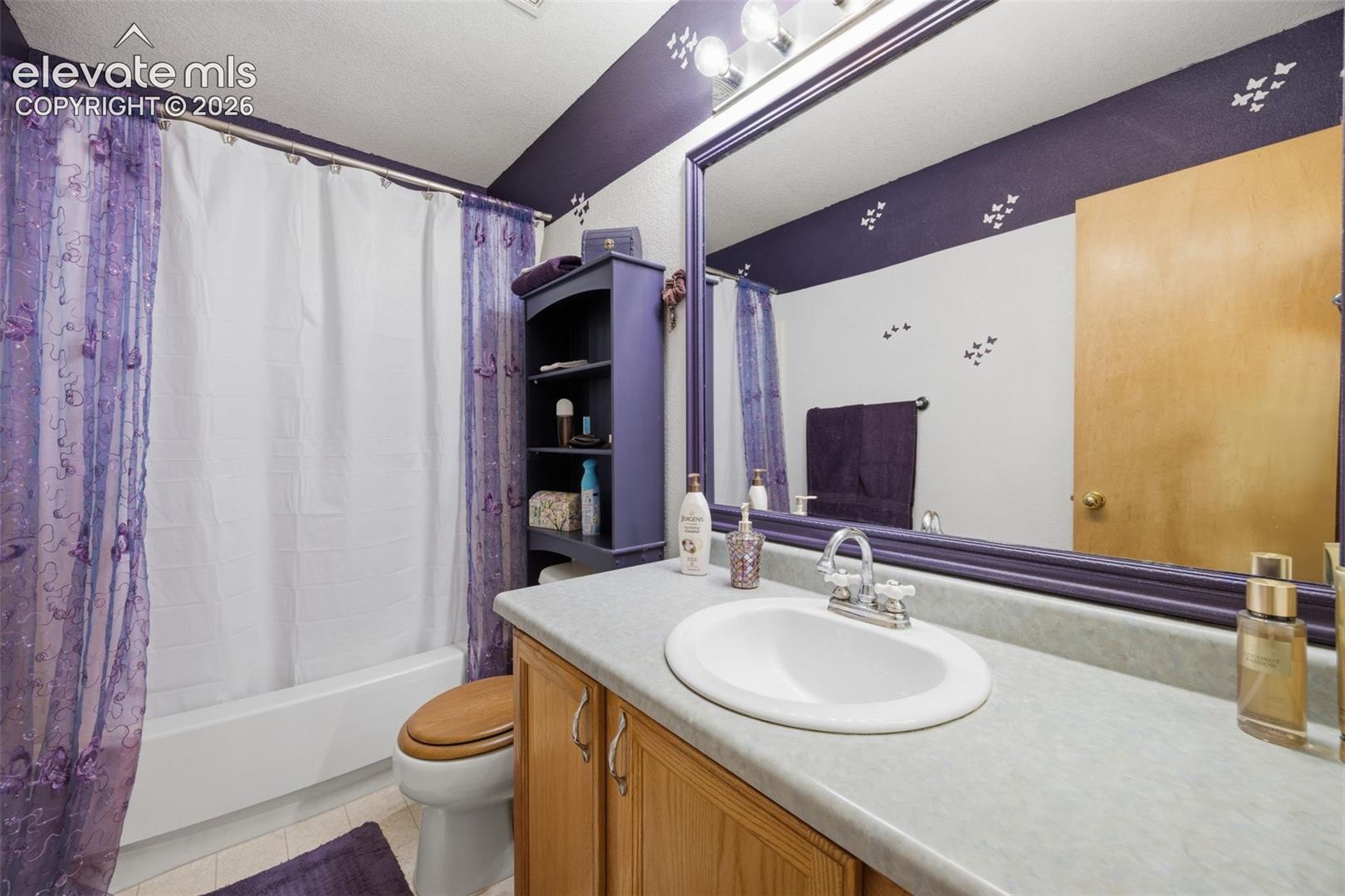 PrimaryBathroom featuring a single vanity with a laminate countertop, undermount sink, and wood-finish cabinetry