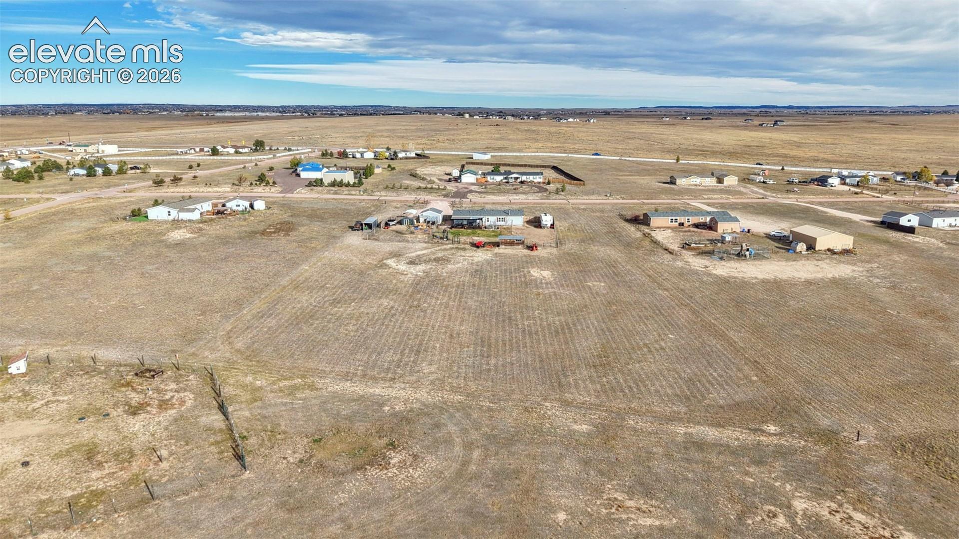 Expansive level lot featuring open acreage, perimeter wire fencing, and rural landscape surroundings