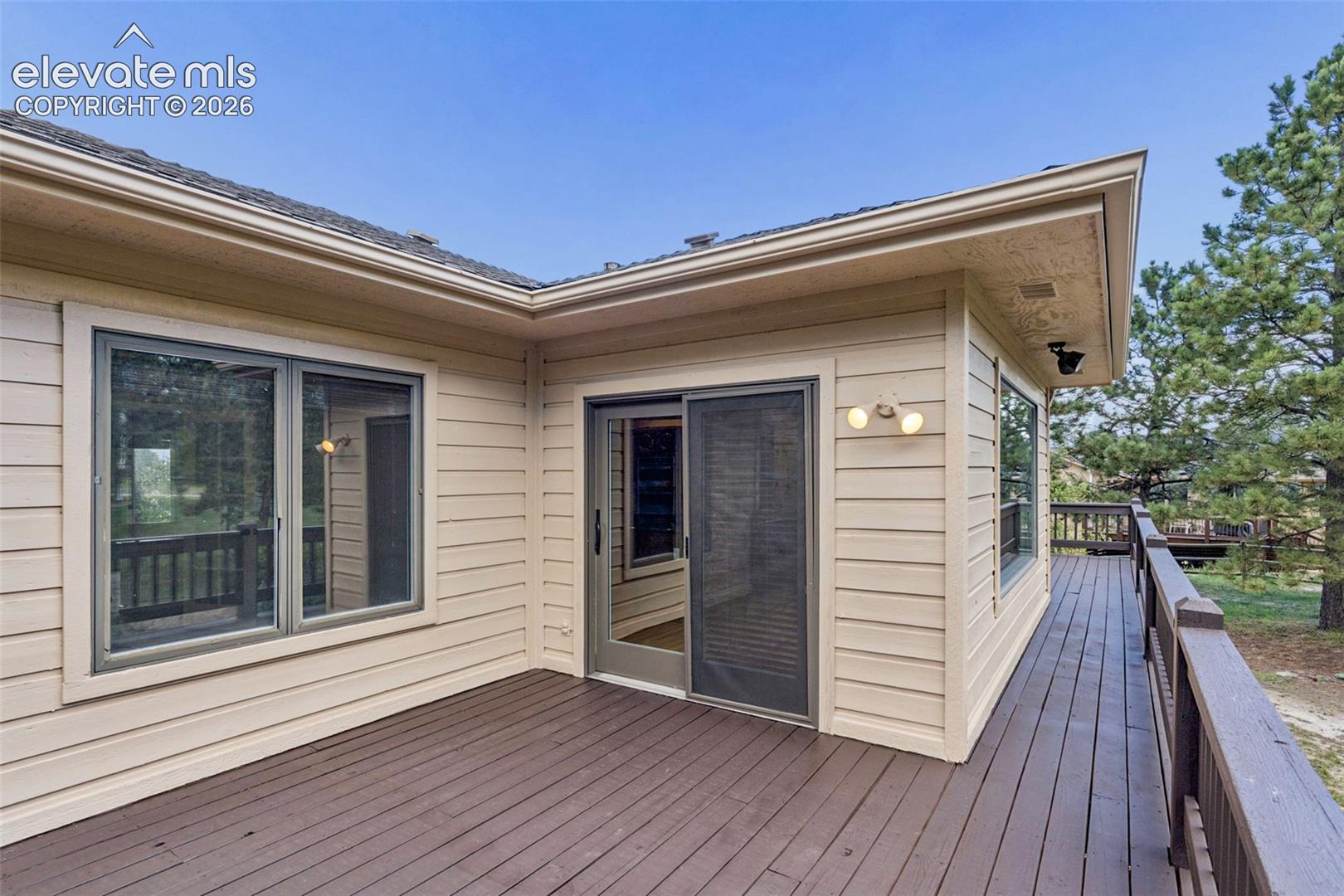 Expansive wood-finish deck with a wood-plank surface, a sliding glass door, and large windows