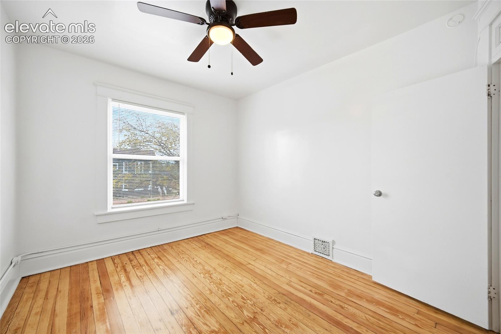 Room featuring wood-finish flooring, a single-hung window with casing, and a ceiling fan with integrated lighting