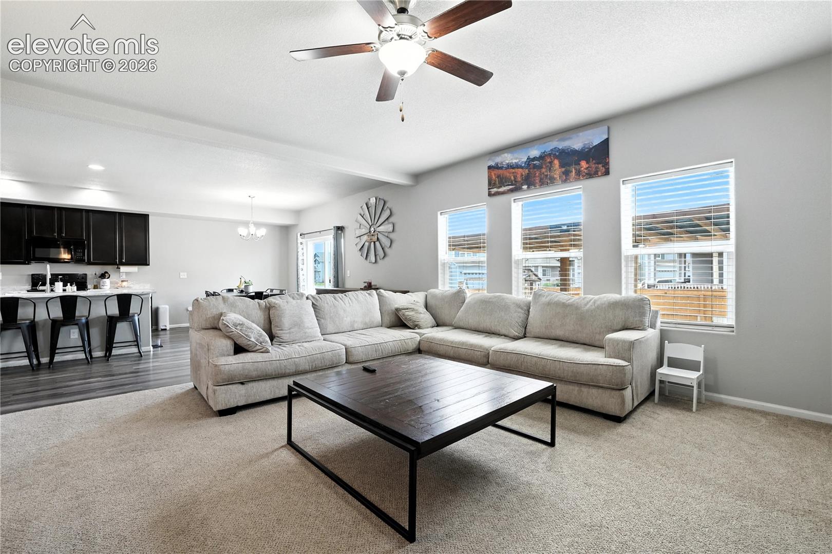 Spacious living area featuring carpeting, multiple windows with blinds, a ceiling fan, and recessed lighting