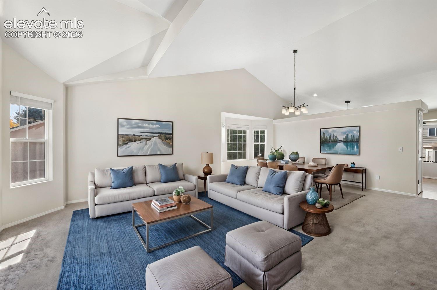 Vaulted ceilings, expansive multi-pane windows, bay window configuration, and an overhead multi-arm chandelier