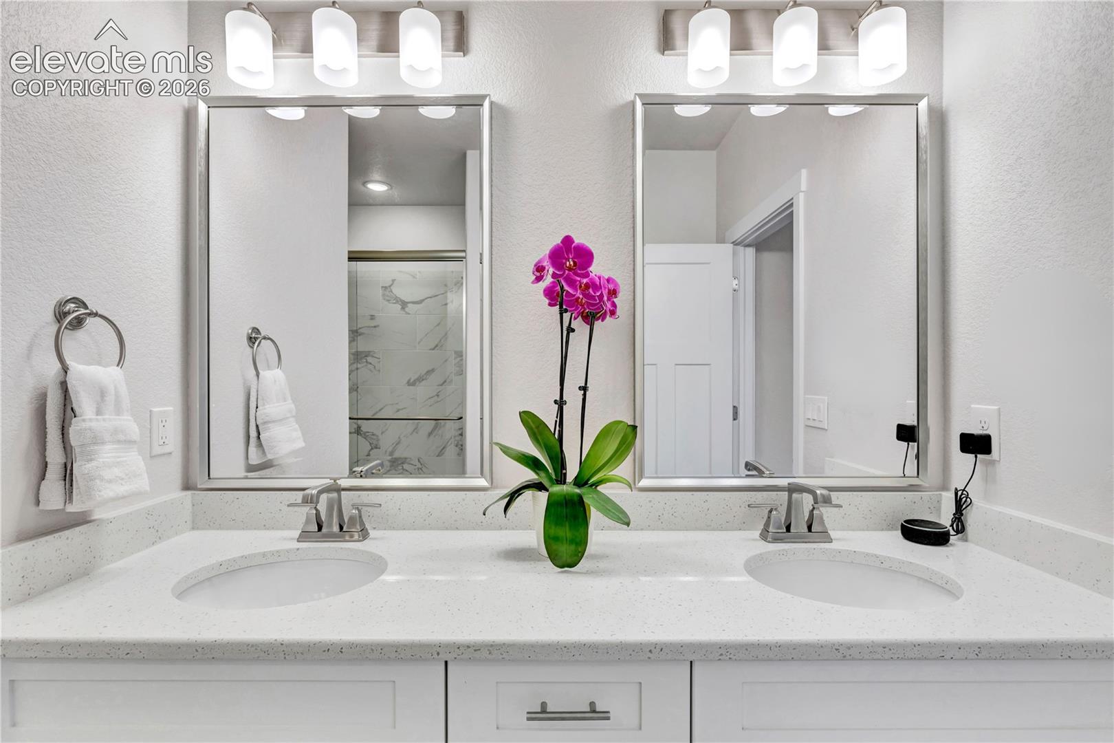 Dual vanity featuring integrated sinks, white cabinetry, chrome fixtures, and rectangular mirrors with overhead lighting