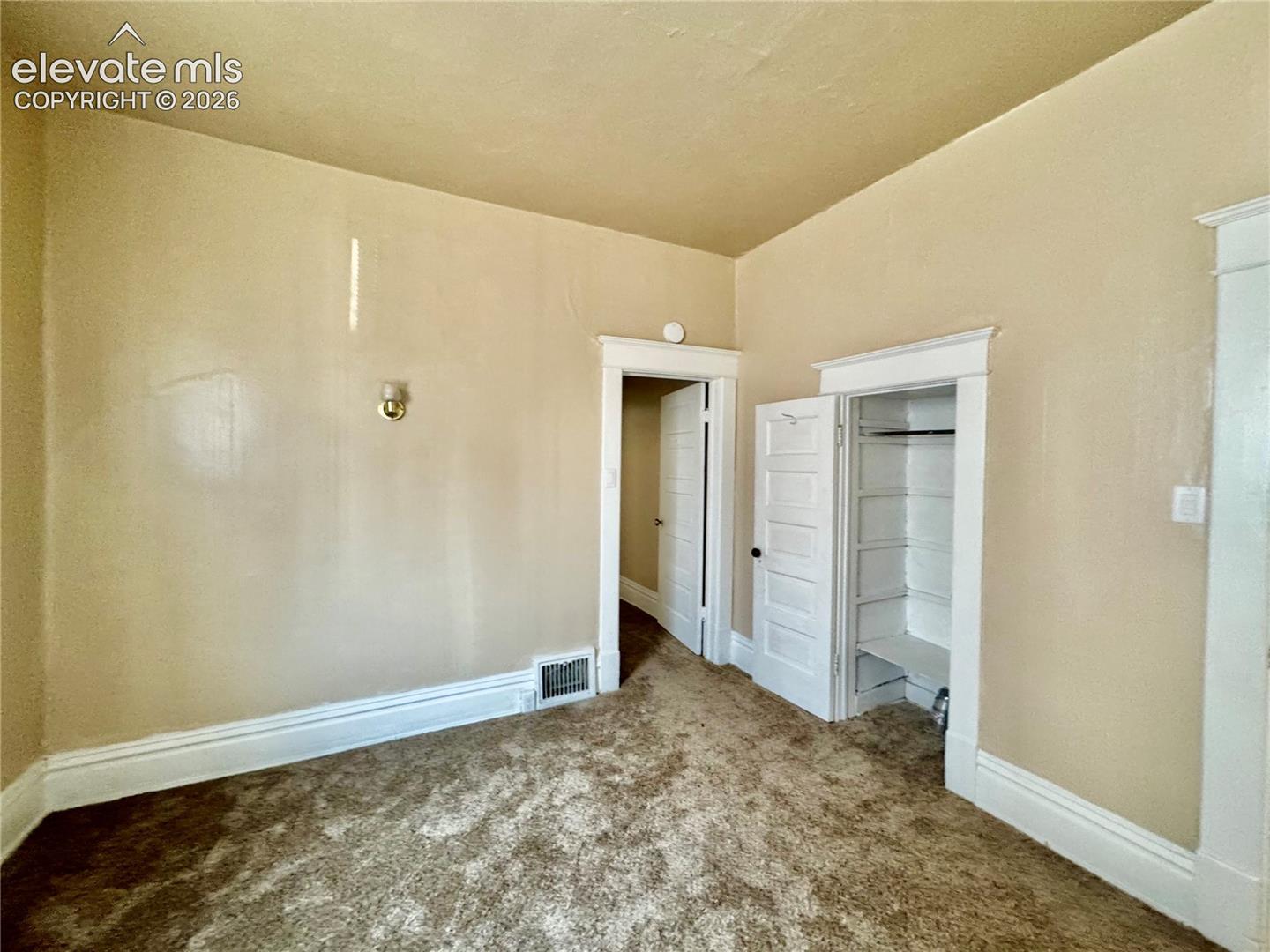 Spacious bedroom with neutral wall finishes, carpeted flooring, and abundant natural light