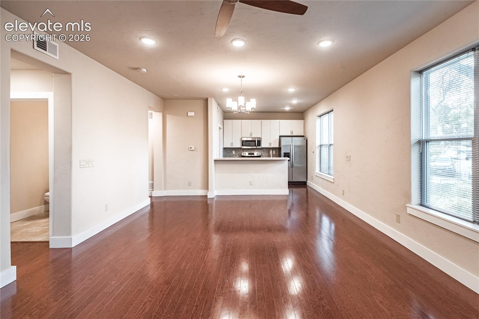 Expansive open-concept living area featuring rich wood-finish flooring, recessed lighting, and a ceiling fan
