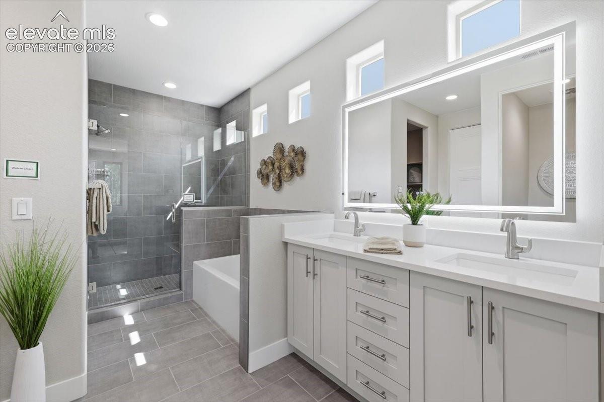 Primary Bathroom with Double Vanities, Quartz Countertops, Heated and Lighted Mirror, Soaking Tub, and Shower with Bench.