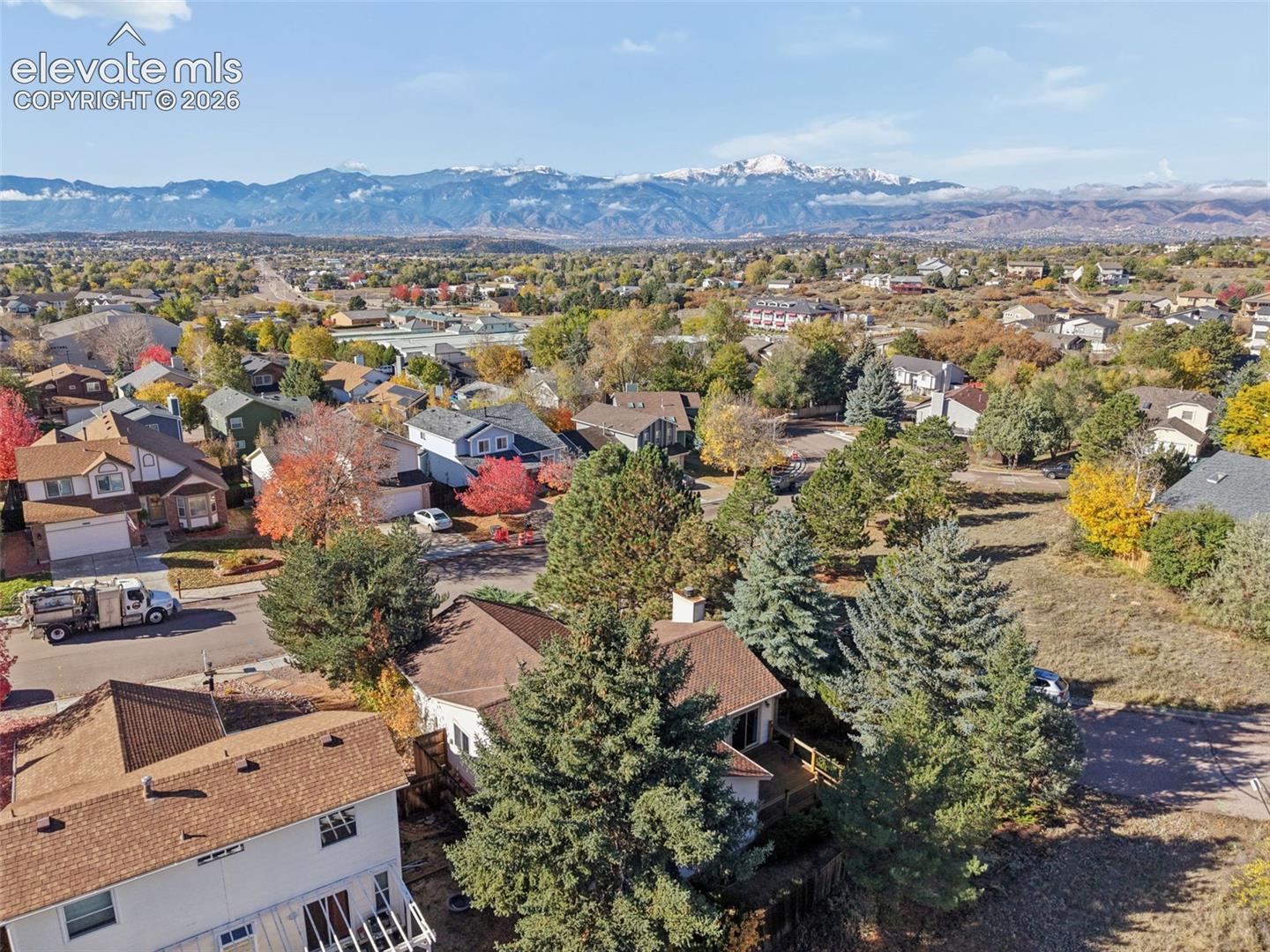 Aerial perspective featuring expansive mountain scenery and mature evergreen trees surrounding the residential lot