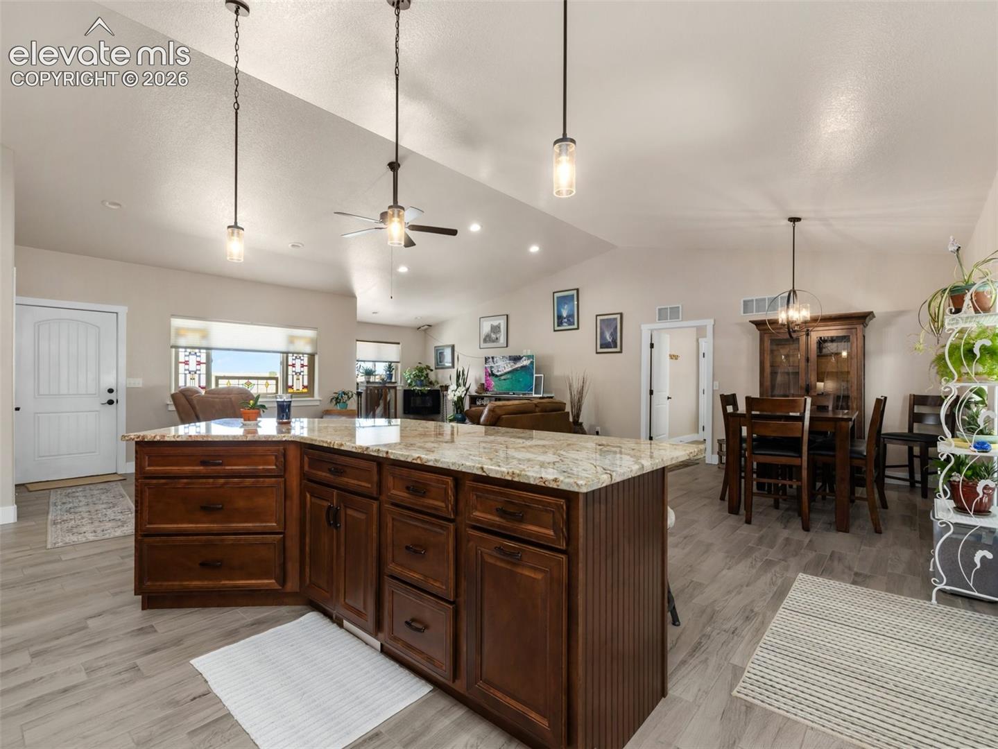 Spacious open-concept living area featuring wood-finish flooring and vaulted ceilings