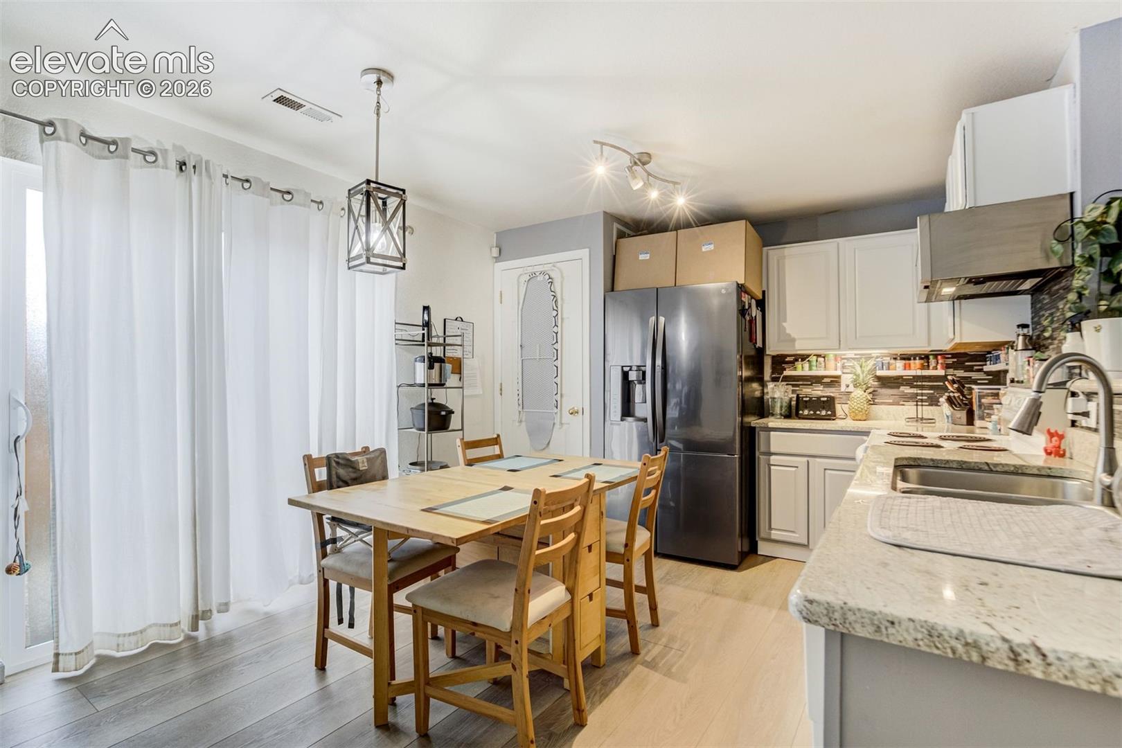 Wood-finish flooring, white cabinetry, light-toned countertops, and a tile backsplash