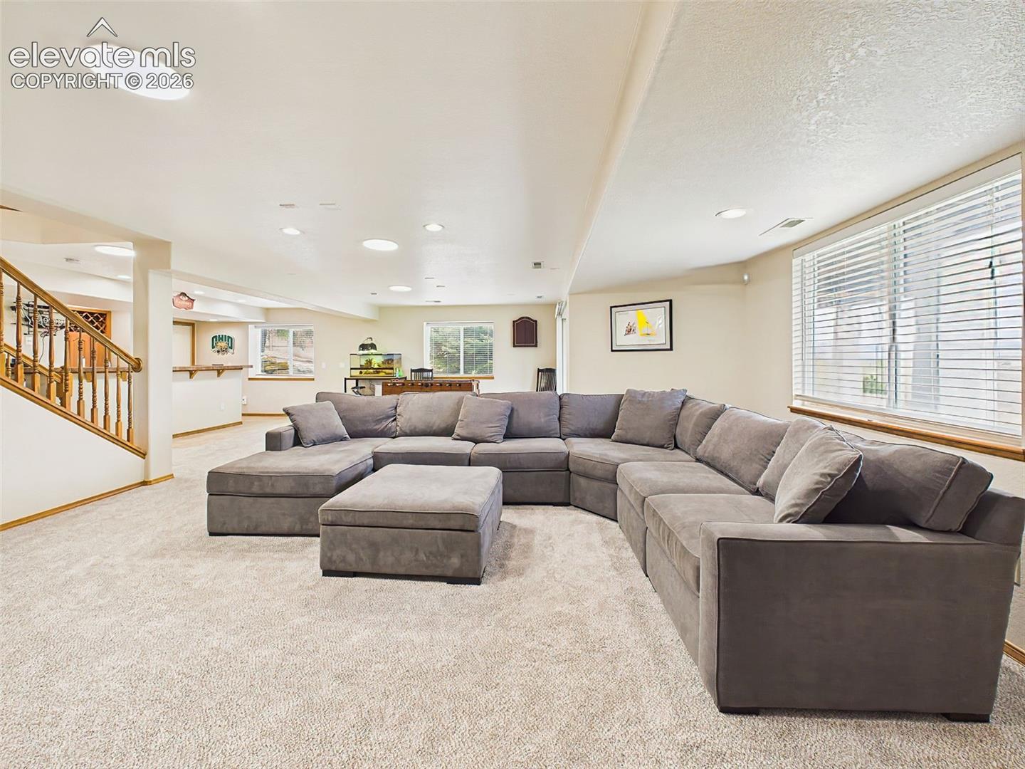 Comfortable family room with oversized sectional seating and abundant recessed lighting, ideal for relaxing or hosting guests.