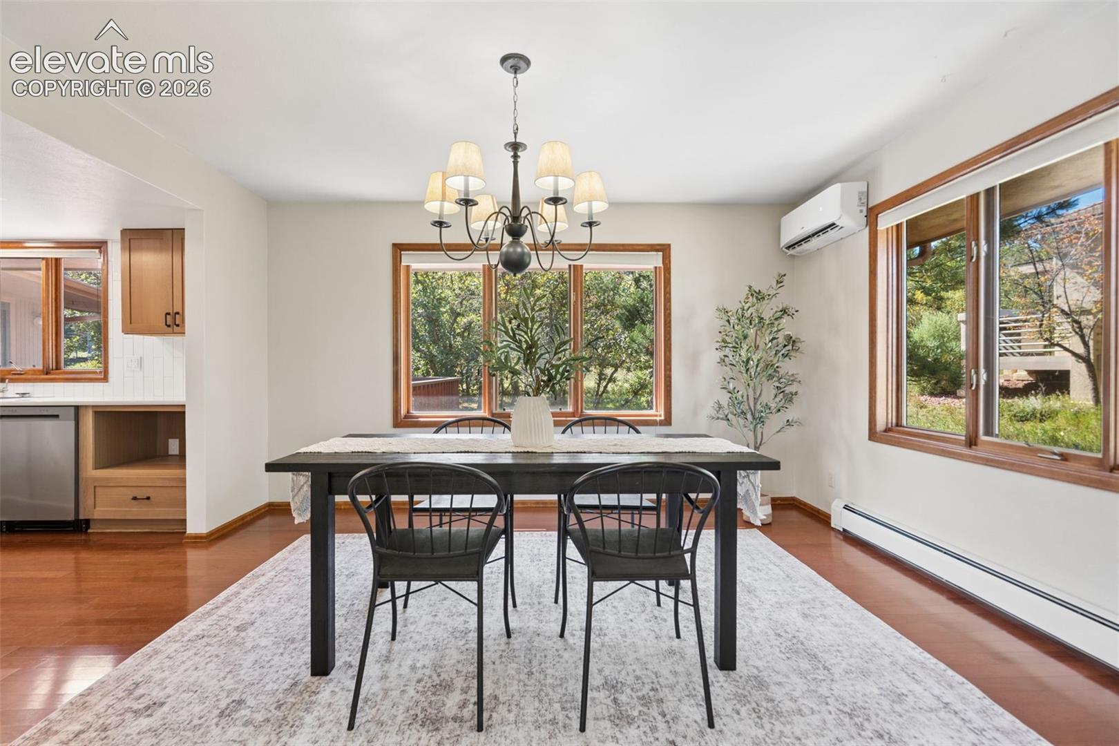 Hardwood flooring, natural wood window trim, stainless steel dishwasher, built-in cabinetry, and a ceiling-mounted chandelier