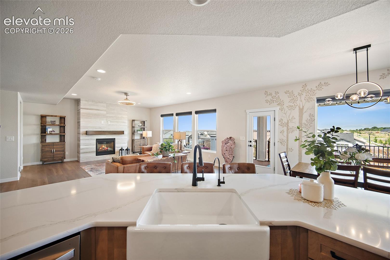 Kitchen island with a farmhouse sink and black faucet, wood-finish cabinetry, white countertop, and recessed lighting