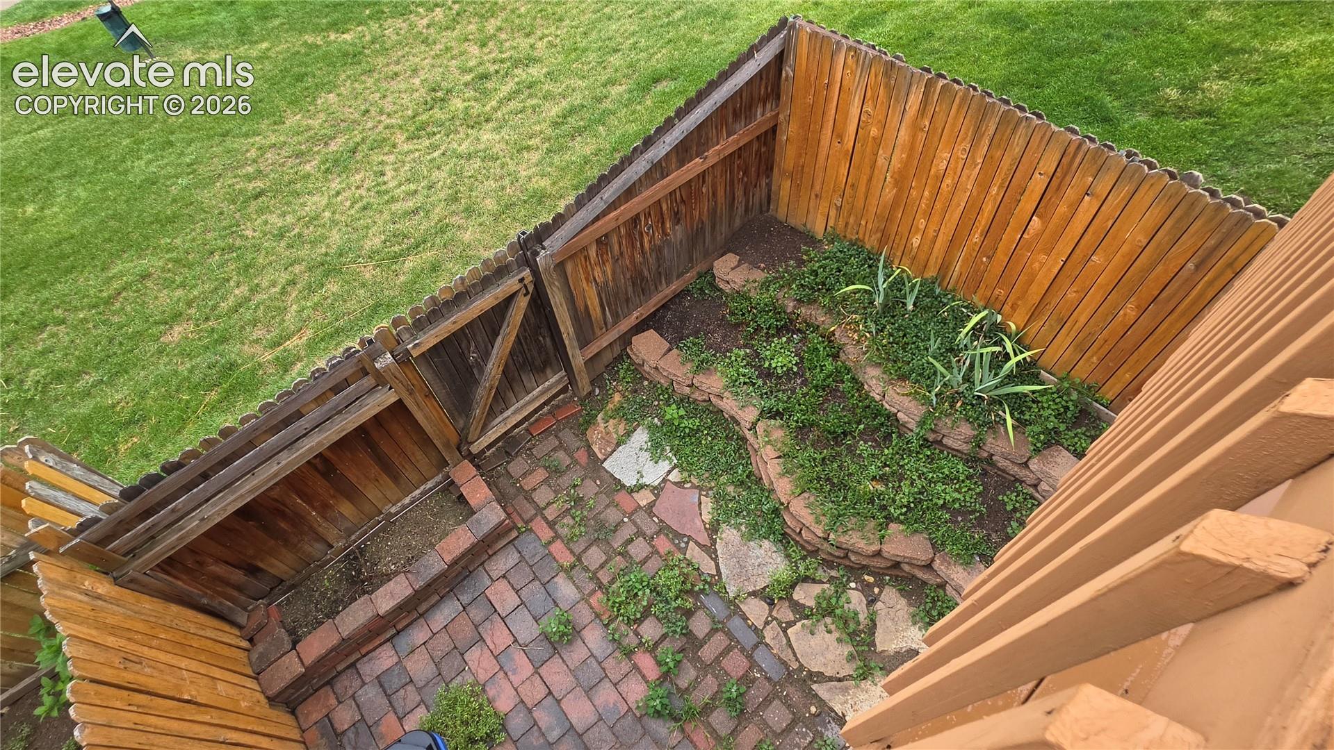 Fenced backyard featuring a brick patio, flagstone accents, and tiered landscaping