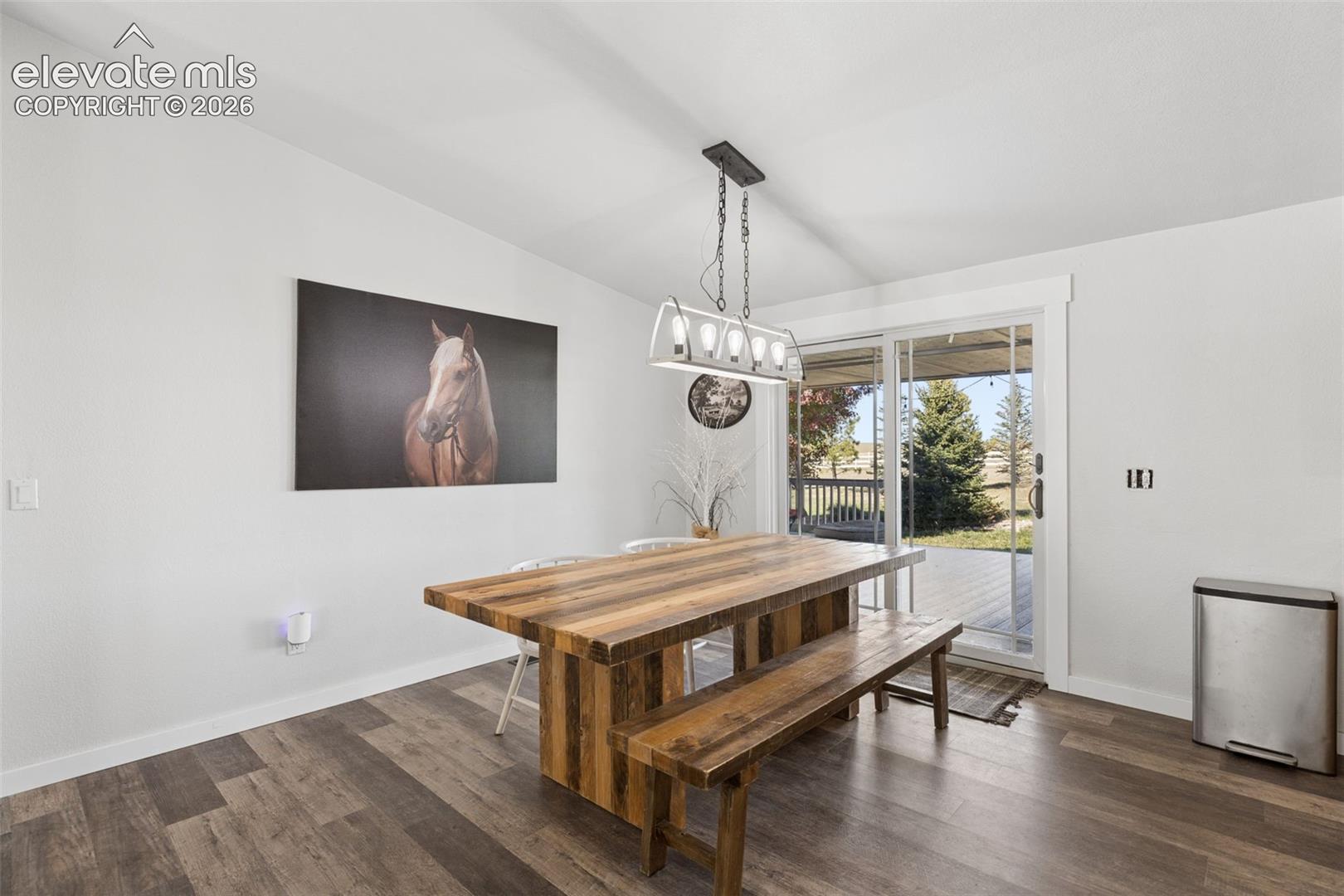 Dining area featuring wood-finish flooring, a contemporary five-light linear pendant fixture, and sliding glass doors with direct exterior access