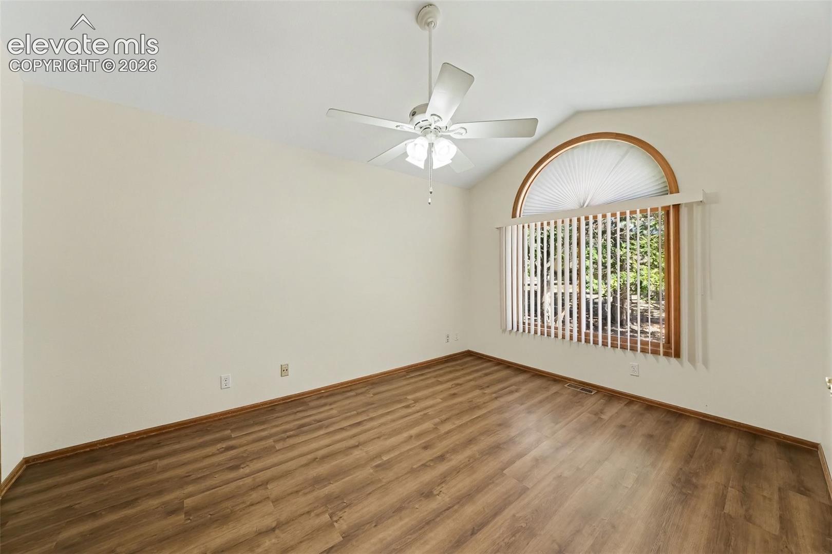 Vaulted ceiling with a ceiling fan, LVP flooring, French doors, and a large arched window