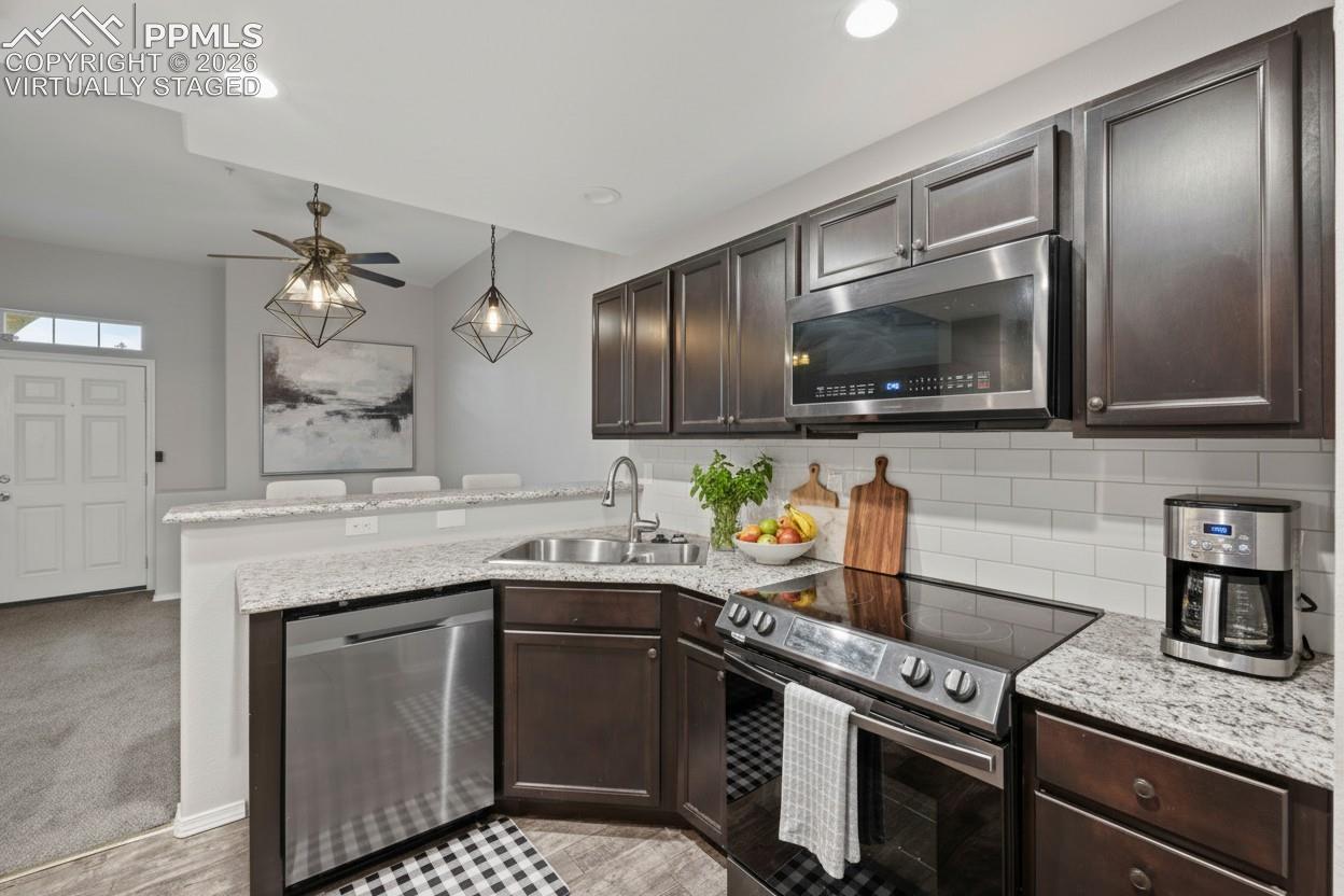 Kitchen featuring stainless steel appliances, dark brown cabinetry, recessed lighting, granite countertops, and baseboards. This photo is virtually staged.