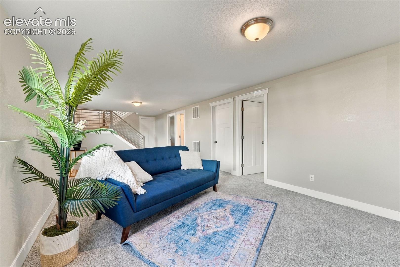 Light gray wall finishes, recessed lighting, white baseboards, gray carpet flooring, and a contemporary metal railing system
