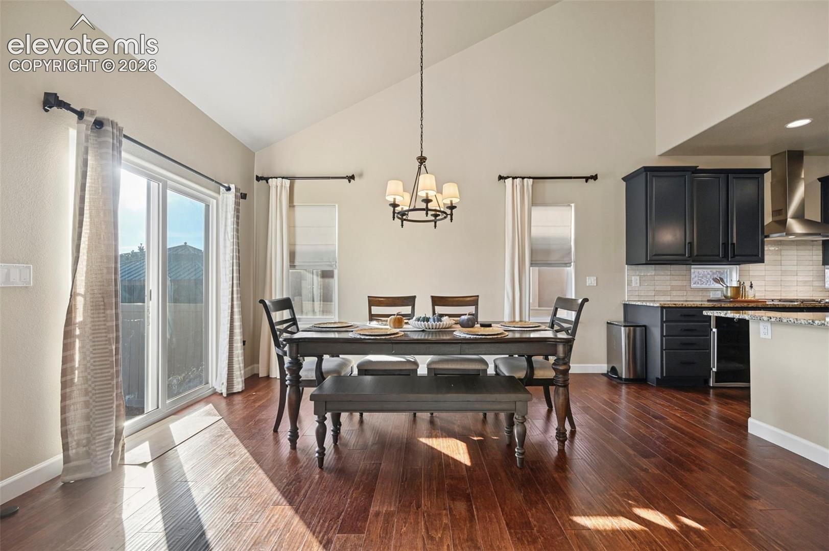 Vaulted ceilings, wood-finish flooring, sliding glass door, recessed lighting, and dark wood-finish cabinetry