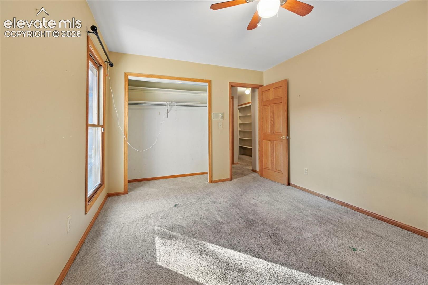 Recessed closet with shelving, wood-paneled door, and wood-framed window