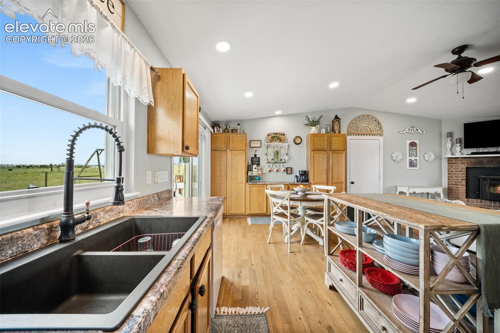 Kitchen featuring a dual basin sink with a black coiled faucet, wood-finish flooring, recessed lighting, and light wood cabinetry