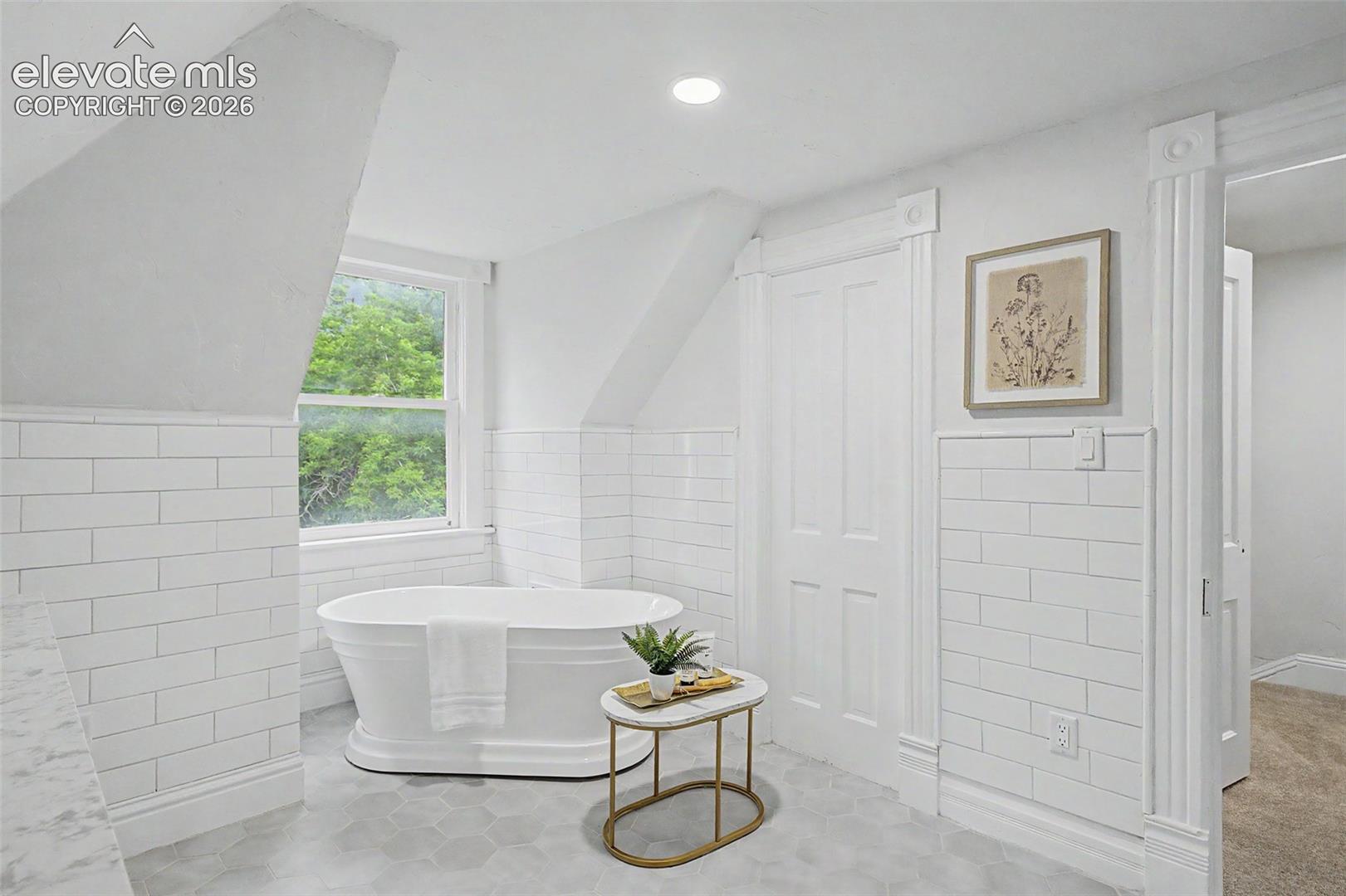 Freestanding tub with subway tile wainscoting and hexagon floor tiles