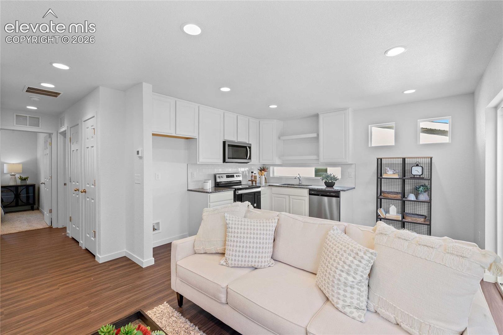 White kitchen cabinetry, stainless steel appliances, dark countertops, recessed lighting, and wood-finish flooring
*photos of a model home*