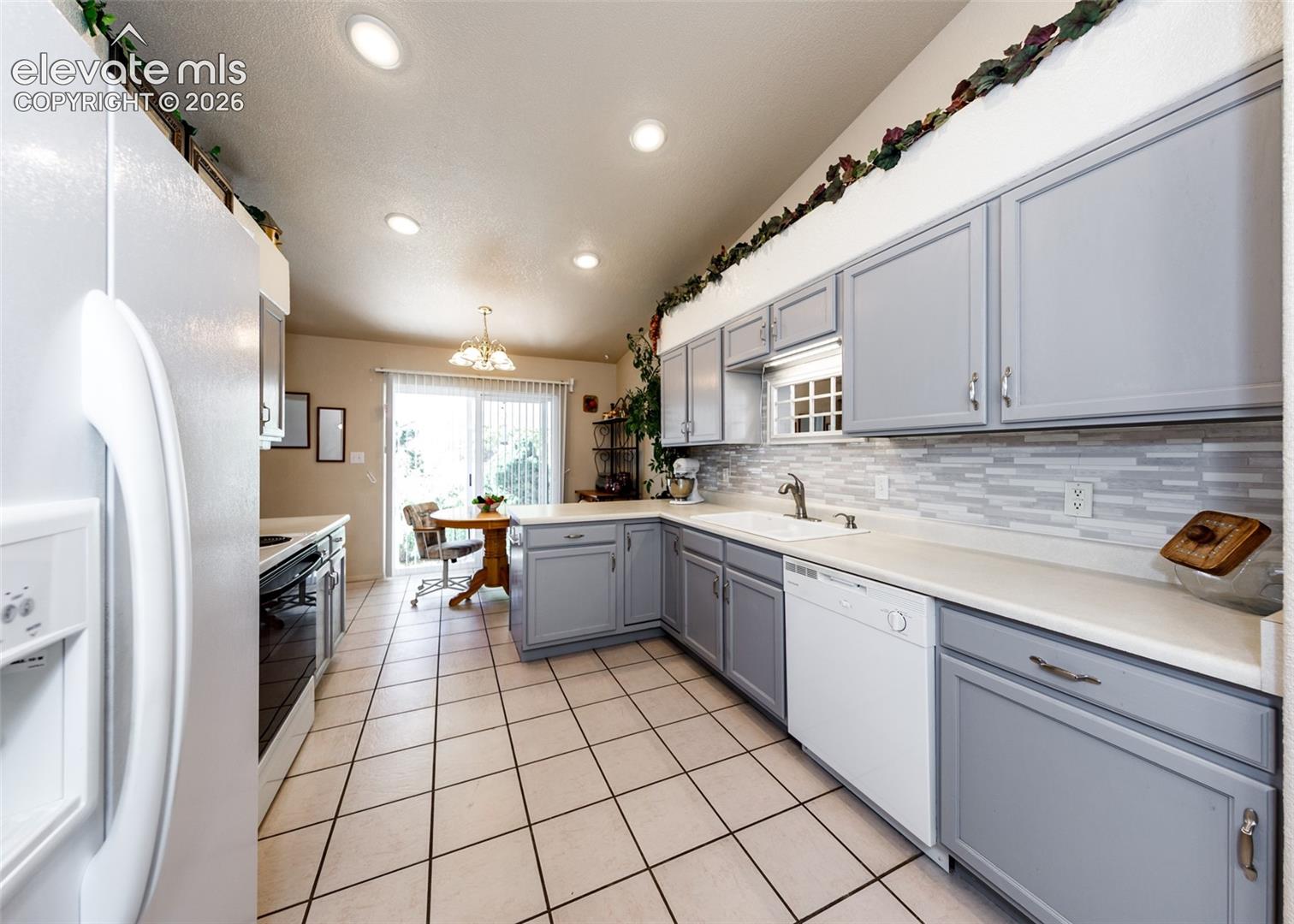 Kitchen featuring gray cabinetry, a linear tile backsplash, solid-surface countertops, recessed lighting, and tile flooring