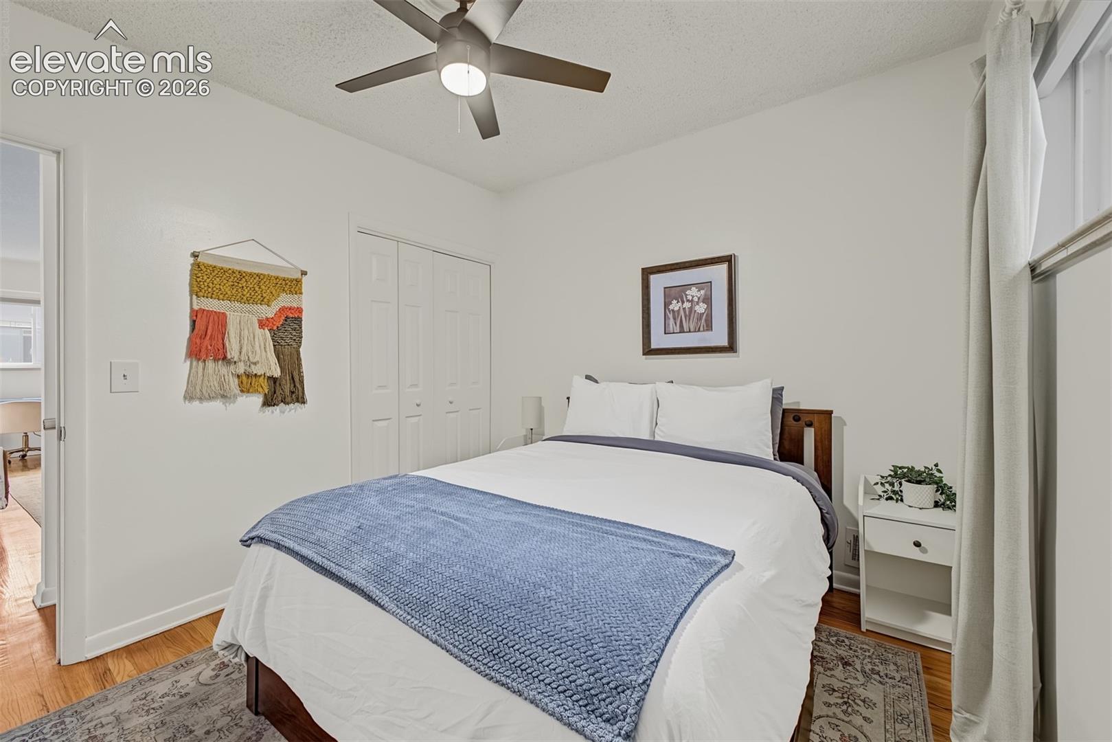 Room featuring wood-finish flooring, a ceiling fan with integrated light, and a double-door closet