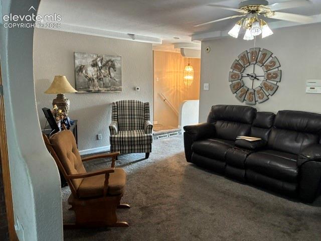 Carpeted living area with a ceiling fan, coved ceiling detail, and a wall-mounted light fixture