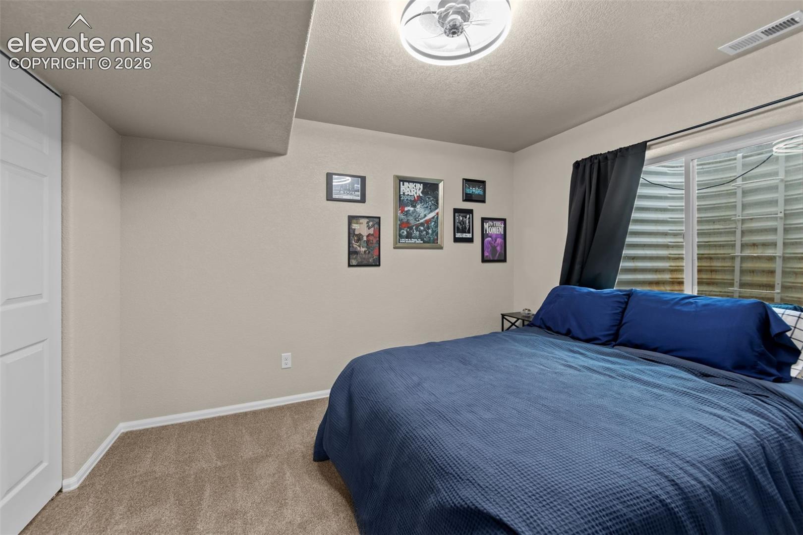 Recessed window with black curtain, ceiling light fixture, and carpeted flooring