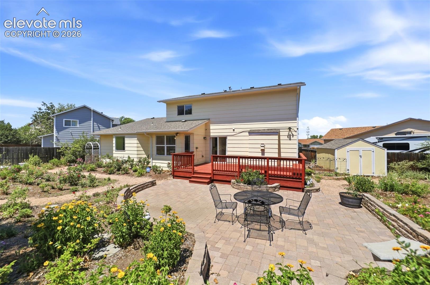 Expansive outdoor living space featuring a paver patio and a multi-level wood deck with red-stained railing