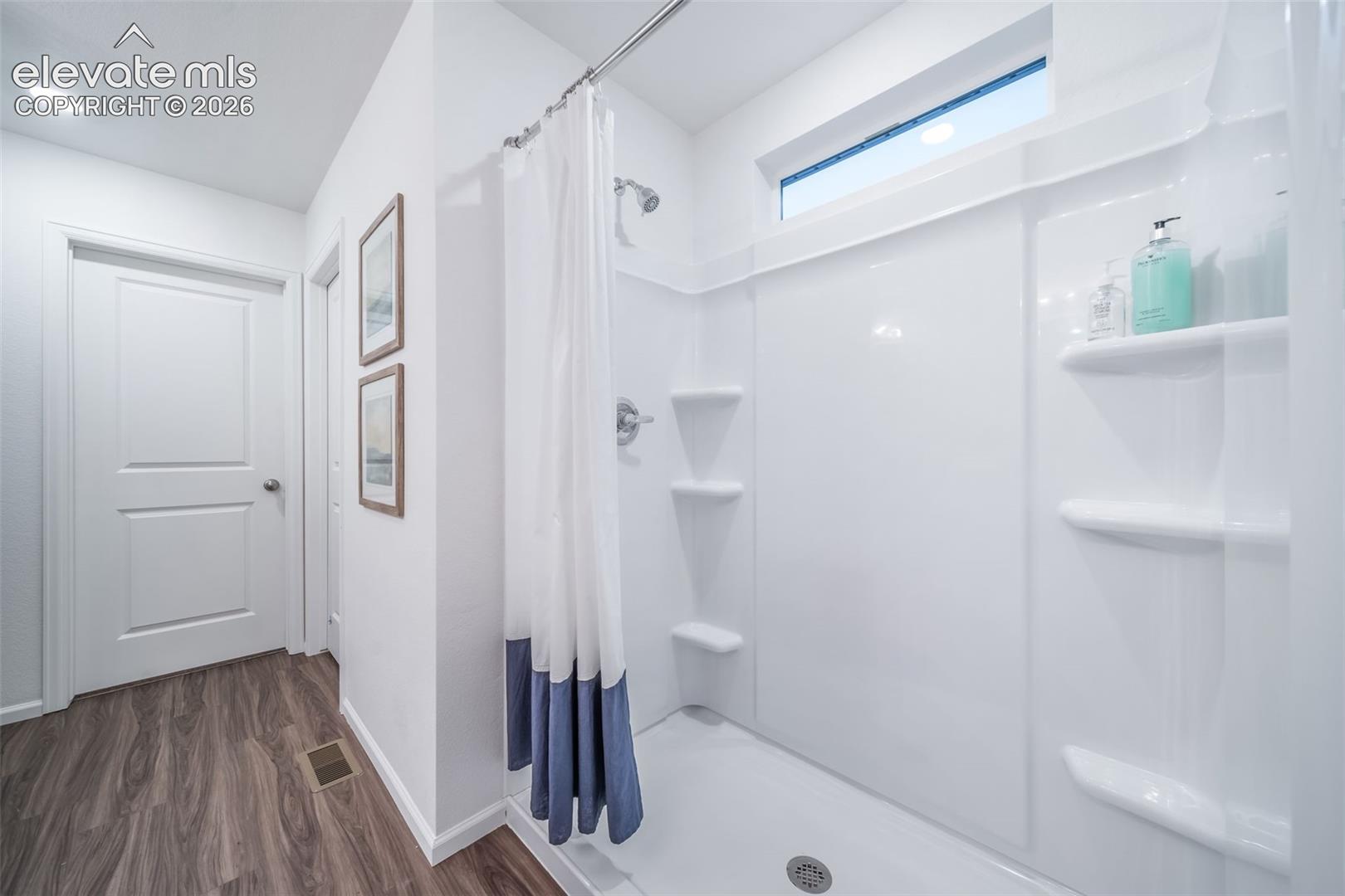 Integrated shower/tub unit with built-in shelving, chrome fixtures, and a high transom window
*photos of a model home*