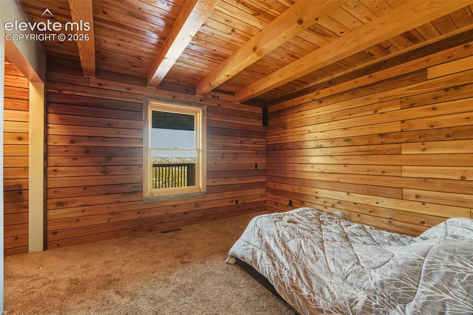 Wood-paneled walls, exposed wood beam ceiling, single window, and neutral carpeting