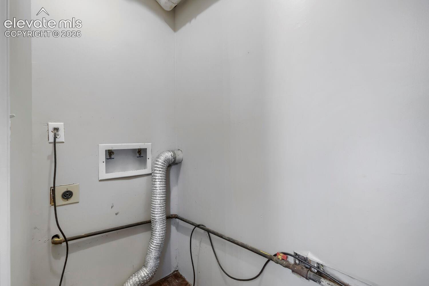 Utility space featuring light gray walls, an electrical outlet, and a dryer vent hookup