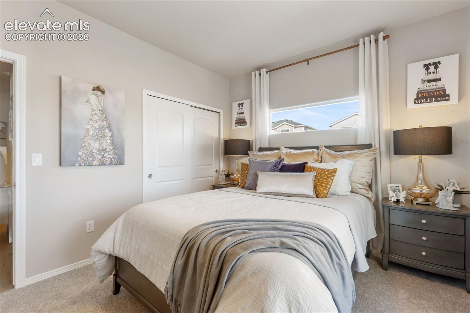 Neutral-toned bedroom featuring carpeted flooring, a horizontal transom window, and a double-door reach-in closet