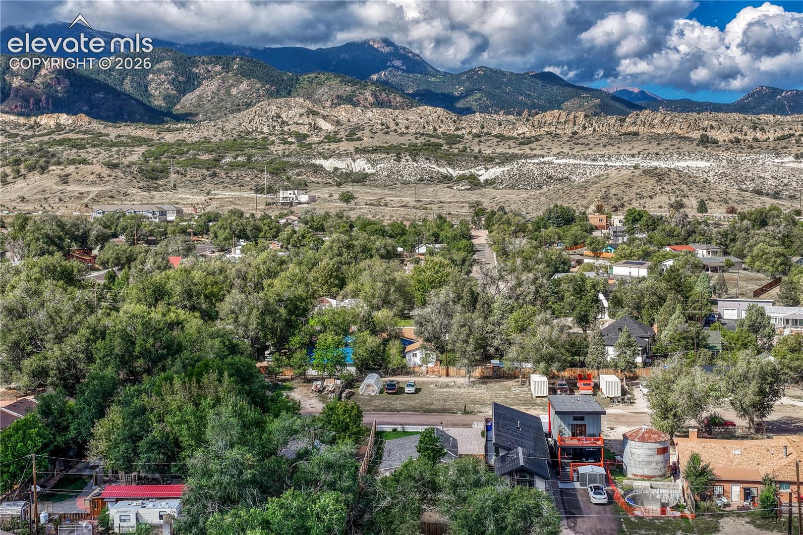 Expansive mountain backdrop with a residential area featuring mature trees and diverse architectural styles