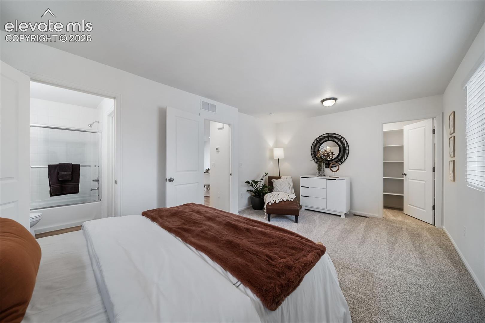 Spacious room featuring neutral carpeting, white interior doors, a window with blinds, and a built-in closet with shelving
*photos of a model home*