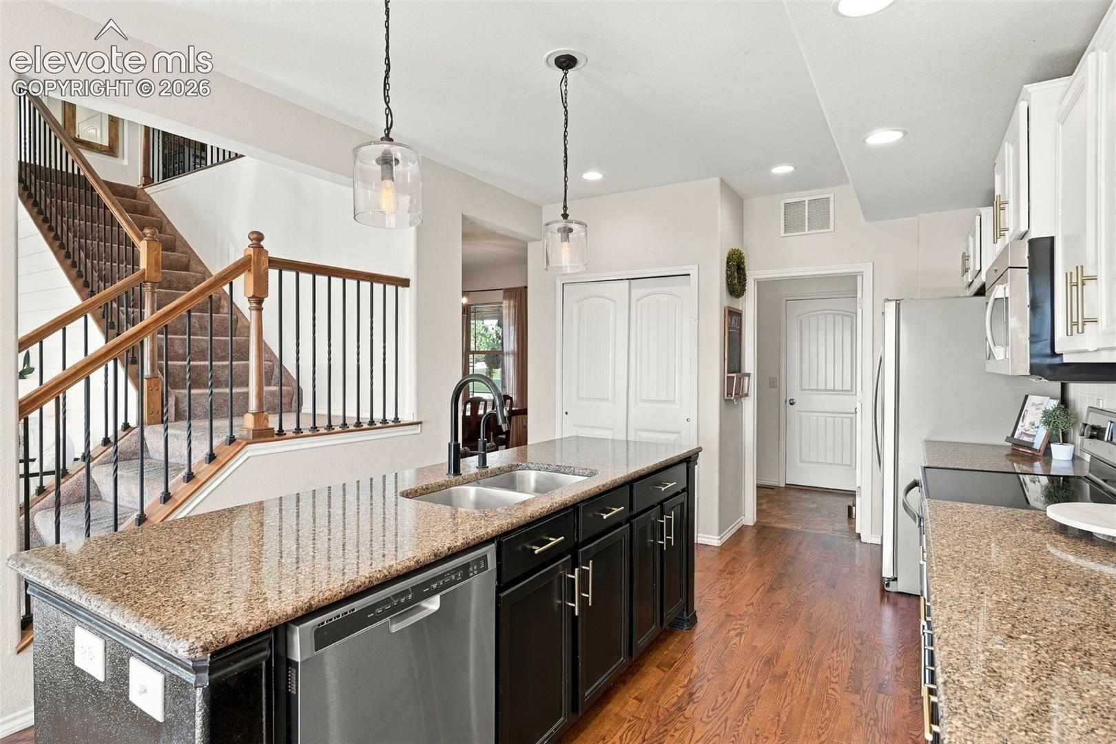 Kitchen featuring a center island, stone countertops, stainless steel dishwasher, dark-finish cabinetry, and wood-finish flooring
