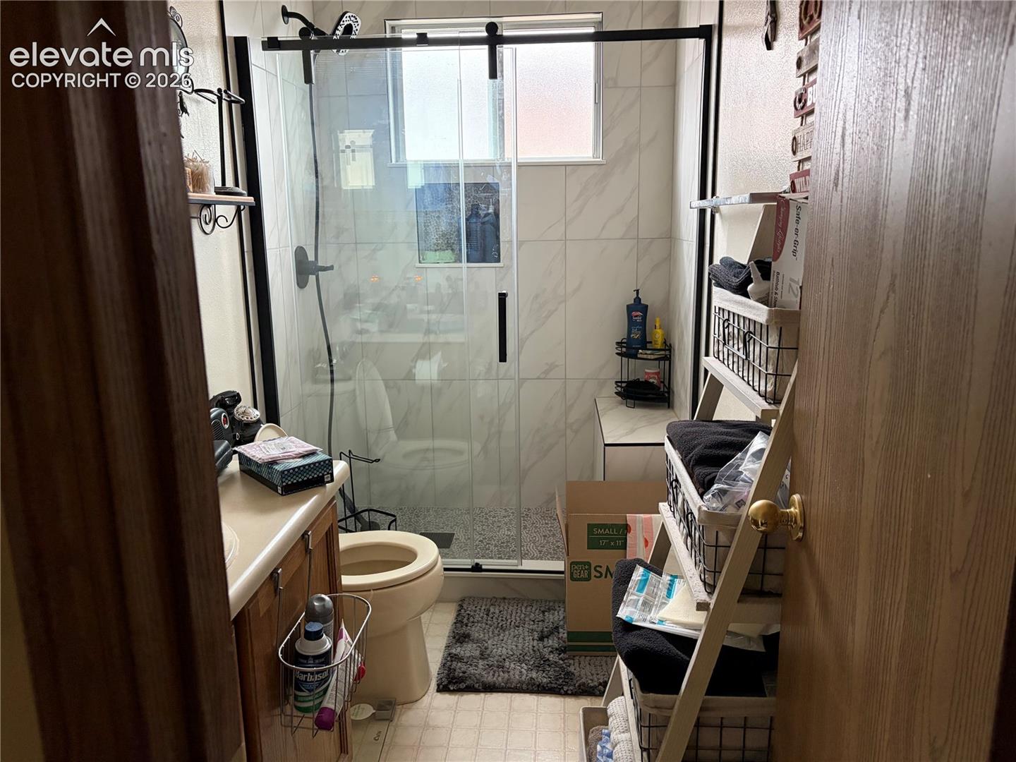 Bathroom featuring a walk-in shower with stone-patterned wall tile, a sliding glass barn-style door, and matte black fixtures