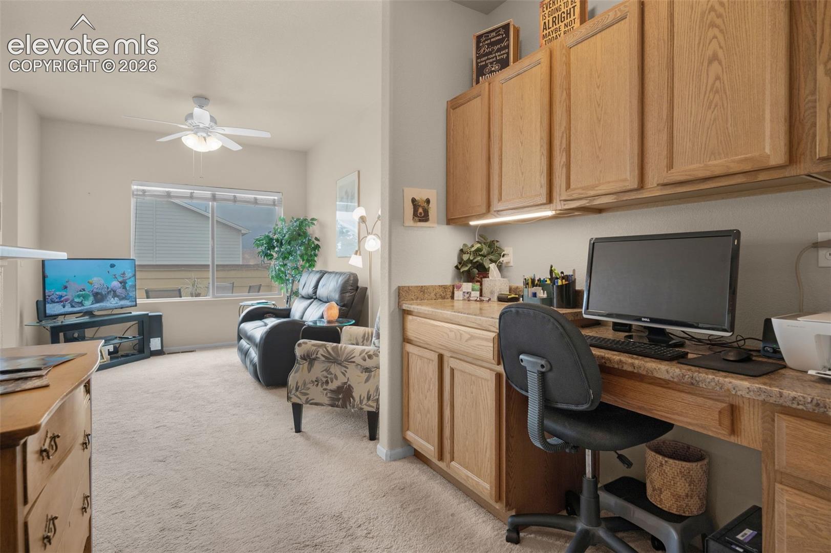 Dedicated office space featuring built-in wood cabinetry, a coordinating countertop, and task lighting
