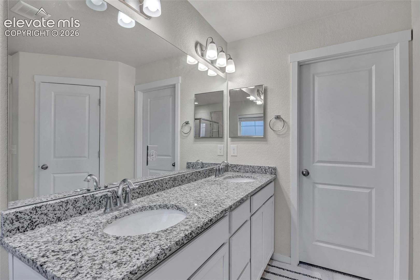 Double vanity with speckled stone countertop and undermount sinks