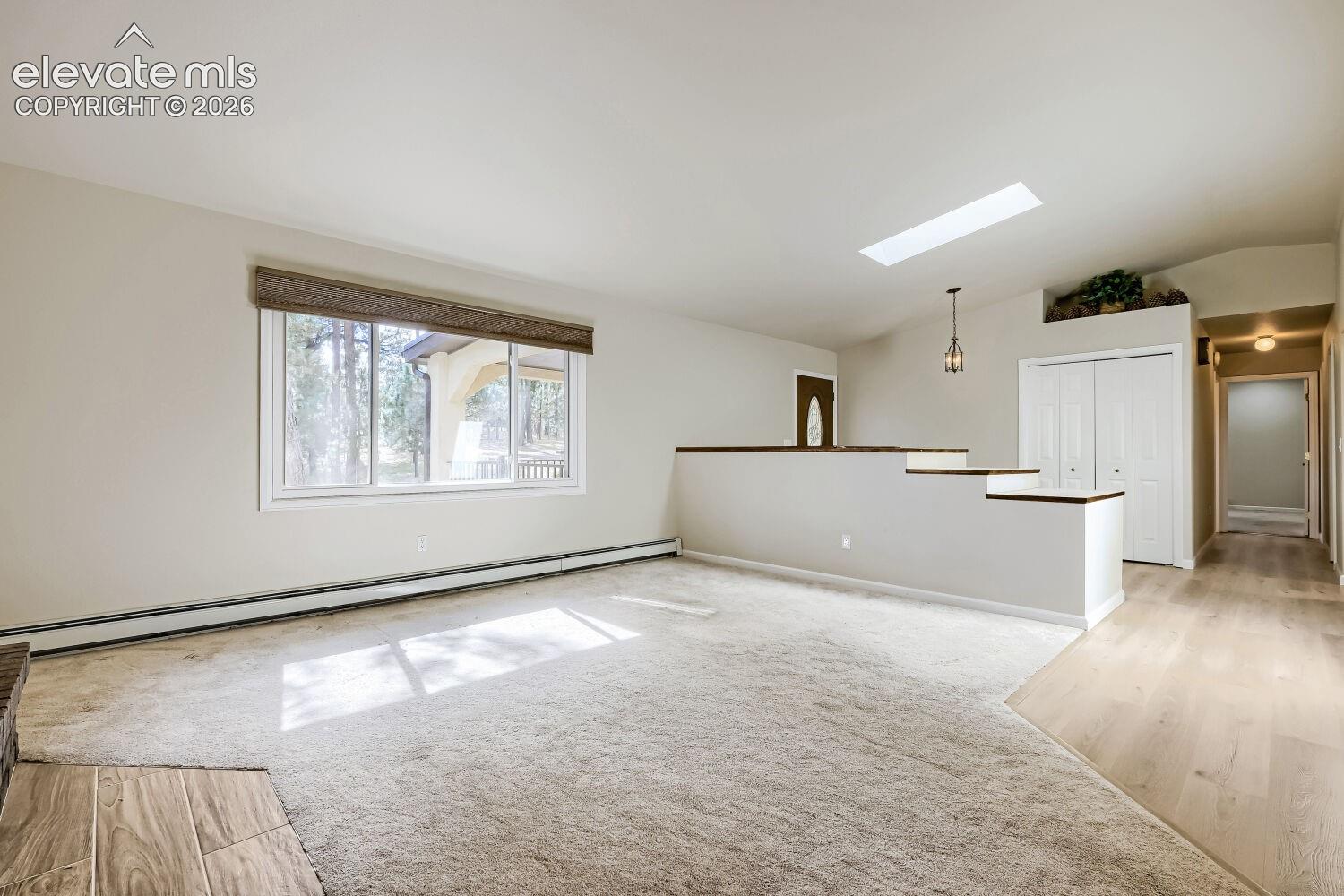 Bright living space with a large window, skylight, and recessed lighting