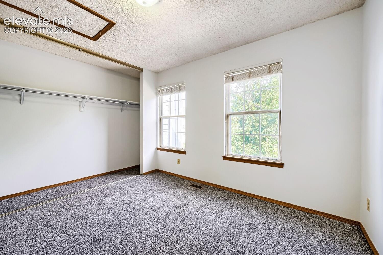 Room with carpet flooring, two windows, and an integrated closet system