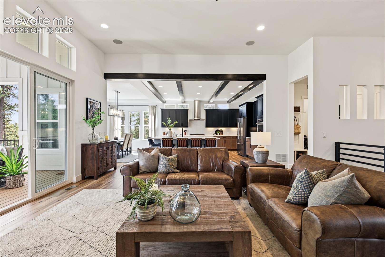 Spacious, light-filled great room featuring expansive windows, soaring ceilings, and an open-concept design that flows seamlessly into the gourmet kitchen and dining area.